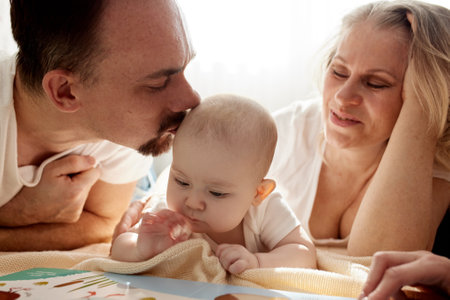 Close-up view of young parents, mom and dad, reading a childrens book to their baby. Family training and education concept. Close-up.の写真素材