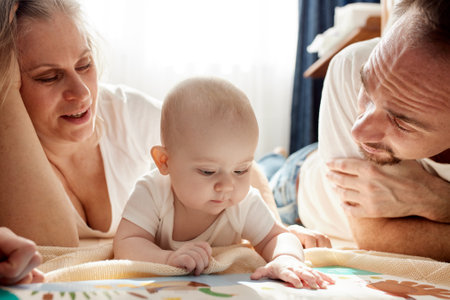 Close-up view of young parents, mom and dad, reading a childrens book to their baby. Family training and education concept. Close-up.の写真素材