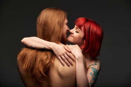 Sexy passionate couple in love in the studio. The womans arms embrace a handsome half-naked man, standing with his back to the camera. Love and passion.の写真素材