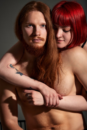 Studio portrait of sexy passionate couple in love. The hands of a woman embrace a handsome half-naked man. Love and passion.の写真素材