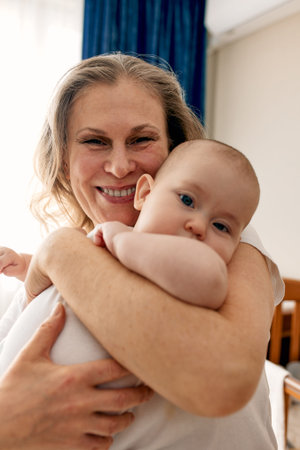 Loving grandmother carries her little granddaughter at home. Bright portrait of a happy grandmother...