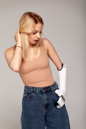 Studio half-length portrait of beautiful young blonde girl with disability wearing sensory bionic...