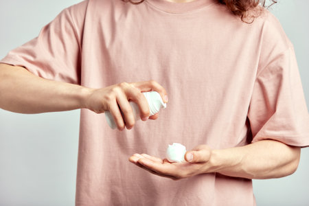 Cropped close-up of a man applying face wash on his hand. Self-caring young man starting his grooming and skincare routine with a skin cleanser, to achieve a fresh and healthy skin. Mens self-care.の写真素材
