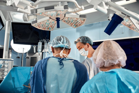 Surgeons team during complex surgical operation in a bright sterile operating room. Doctors leaned over patient using modern surgical instruments and clamps. Precision medicine, saving patients life.の写真素材