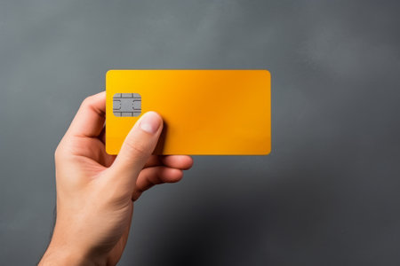 Close-up of male hand holding yellow bank credit card. Online payment concept. Isolated on grey background. Mockup, copy space.の素材