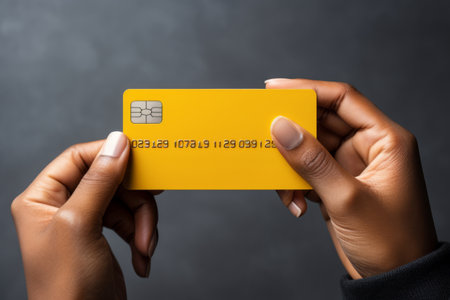 Close-up of male hands holding yellow bank credit card. Online payment concept. Isolated on grey background. Mockup, copy space.の素材
