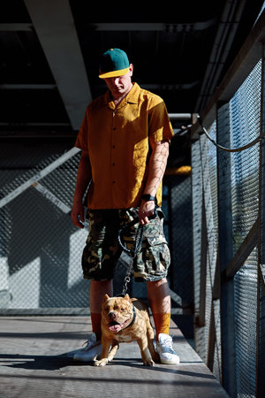 young stylishly dressed man with american bully dog on city streets
