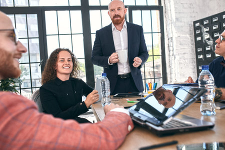 Beautiful business people are using gadgets, talking and smiling during the conference in office
