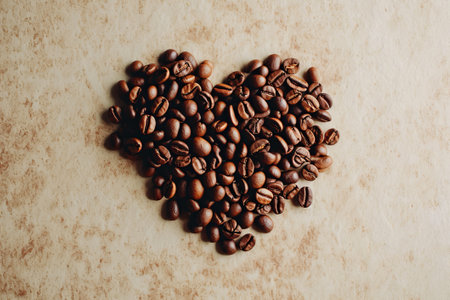 Roasted coffee beans in a heart shape. Coffee beans pattern on a craft paper background. Valentines day for coffee lovers. Copy space.の素材