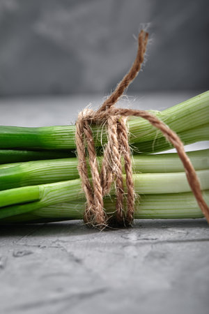 Fresh green onions tied with a rope, close-up, food and health concept with space for text, gray background.の写真素材