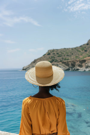 Woman gazing at the ocean in tropical destination with serene skyの素材