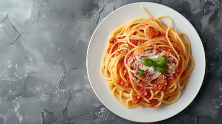 Top view of Spaghetti Bolognese in a white plate on black slate background with copy space. Italian pasta with minced beef sauce, tomatoes, parmesan cheese and fresh basil. Classic Italian cuisine.の素材