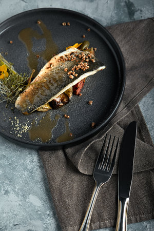 Grilled seabass with eggplant and lime. Horizontal top view, top shot. Copy space, gray concrete marble background, soft light. Food Fashion Photo.の写真素材