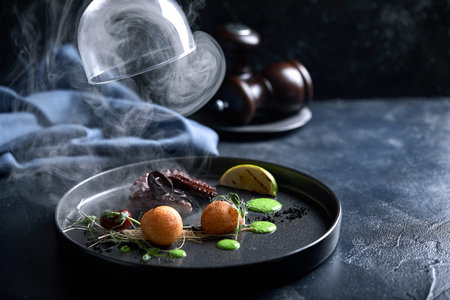 Grilled grilled octopus served with smoke under the hood, food show, low key. Copy space, food...