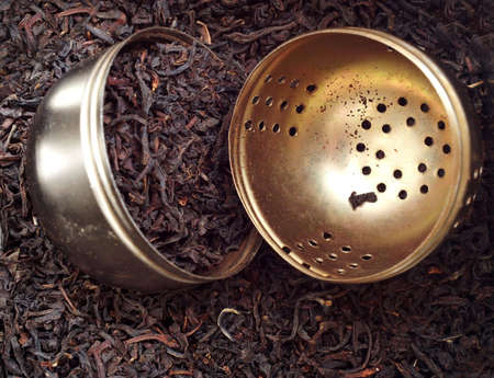 Opened metal tea infuser with dried tea leavesの写真素材