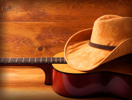 Guitar and cowboy hat on wood background for text or designの写真素材