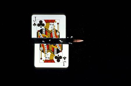 A jack of clubs is shown being shot in half by a bullet. Horizontal shot.のeditorial素材