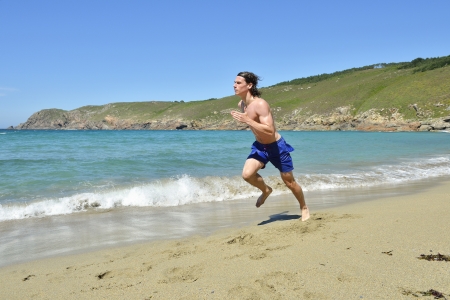 young sportsman running on the beachの写真素材