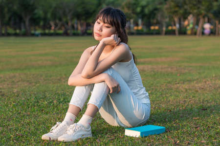 Girl sitting under the sun on the grass fieldの写真素材
