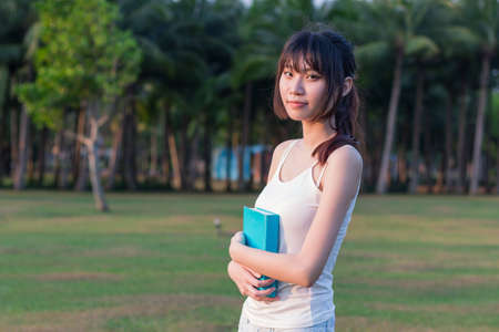 Girl sitting under the sun on the grass fieldの写真素材
