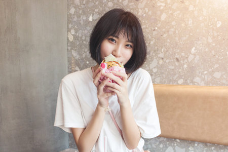 Girl having fun eating burger in restaurant