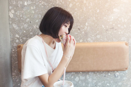 Girl having fun eating burger in restaurantの写真素材
