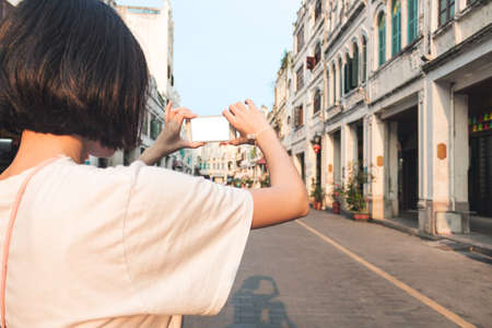 Girl taking pictures with mobile phone in scenic areaの写真素材