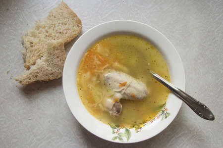 Soup in a plate, spoon and bread on wooden tableの写真素材