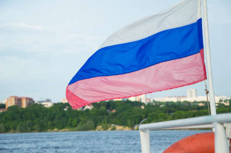 closeup of the flag on the stern of a recreational boat and the city in the backgroundの写真素材