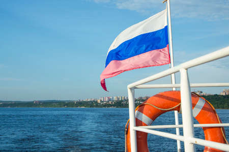 closeup of the flag on the stern of a recreational boat and the city in the backgroundの写真素材