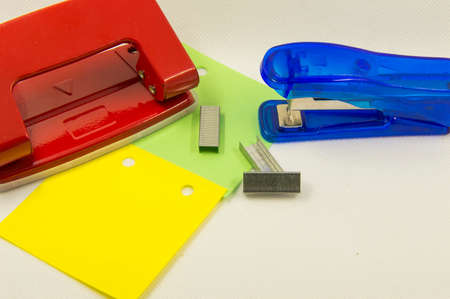 sheets of paper and a hole punch on a white backgroundの写真素材