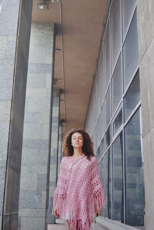 Cute curly hair girl standing between walls with head upの写真素材