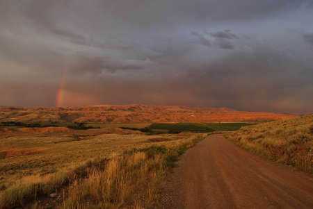 nature landscape of fields and heavy clouds with rainbow in mountains, wyoming, usaの写真素材