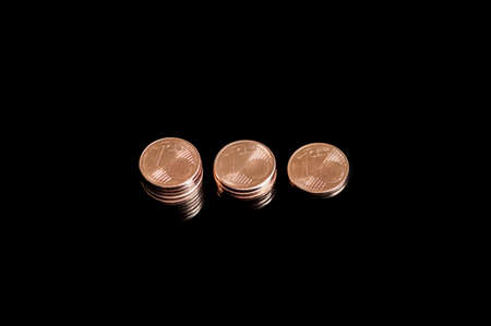 Close-up of three shrinking stacks of euro cent coins isolated on black backgroundの写真素材