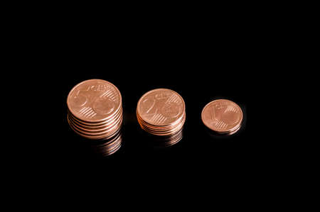 Close-up of three shrinking stacks of euro cent coins isolated on black backgroundの写真素材