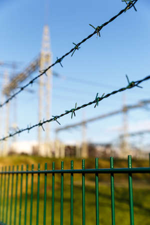 Electricity pylon and barrier fence against  blue skyの写真素材