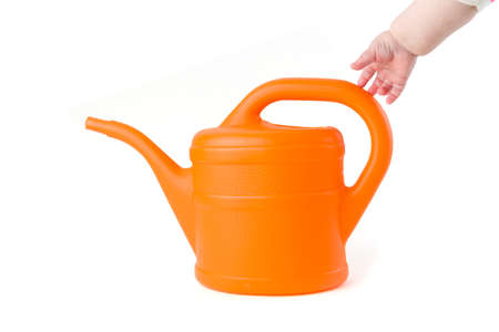 Baby trying to grab a orange watering can on white backgroundの写真素材
