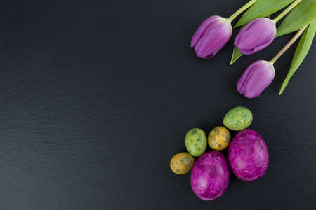 Colorful easter and quail eggs and tulip flowers on stone table. Top view with copy spaceの写真素材