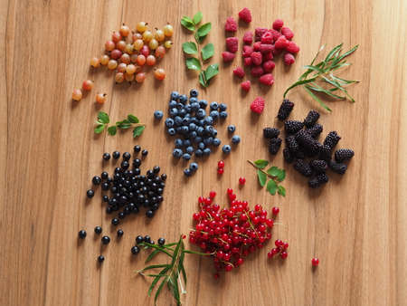 summer berries on a wooden table with greensの写真素材