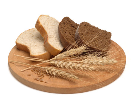 freshly baked bread and wheat on wooden cutting board isolated on white background, top view