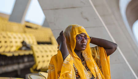 African woman holding in her head shawl on an empty audience stand in Accra Ghana west Africaの写真素材