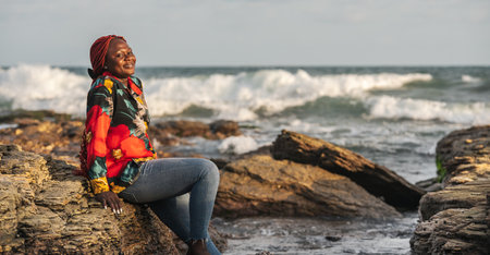 African woman sitting on the beach cliffs at sunset in Accra Ghana West Africaの写真素材