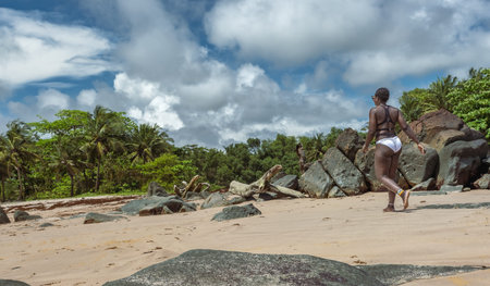 African woman walking on an empty beach against the jungle in Axim Ghana West Africaの写真素材