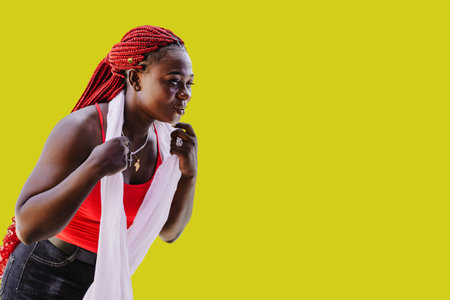 African woman with red rasta hair holding her white shawl with yellow backgroundの写真素材