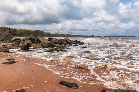 African beach with Black dark boulders lying along the coast of Axim Ghana West Africaの写真素材