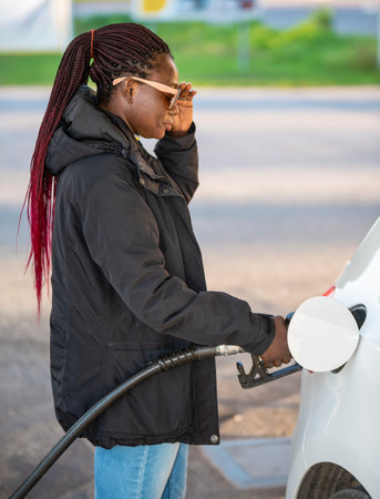 African woman fills the car with diesel at very high prices during the fall
