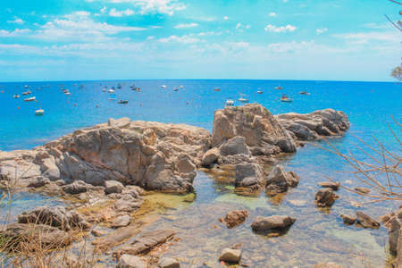 Rocky coast in the Mediterranean with fishing boats in the backgroundの写真素材