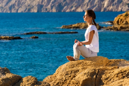 Sexy young woman practicing yoga by the beachの写真素材