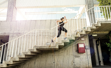 Running woman in black sports outfit, running up the stairs 