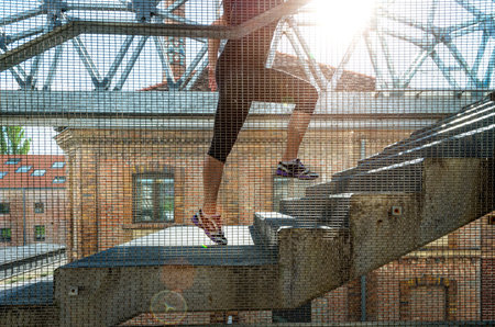 Running woman in black sports outfit, running up the stairs 